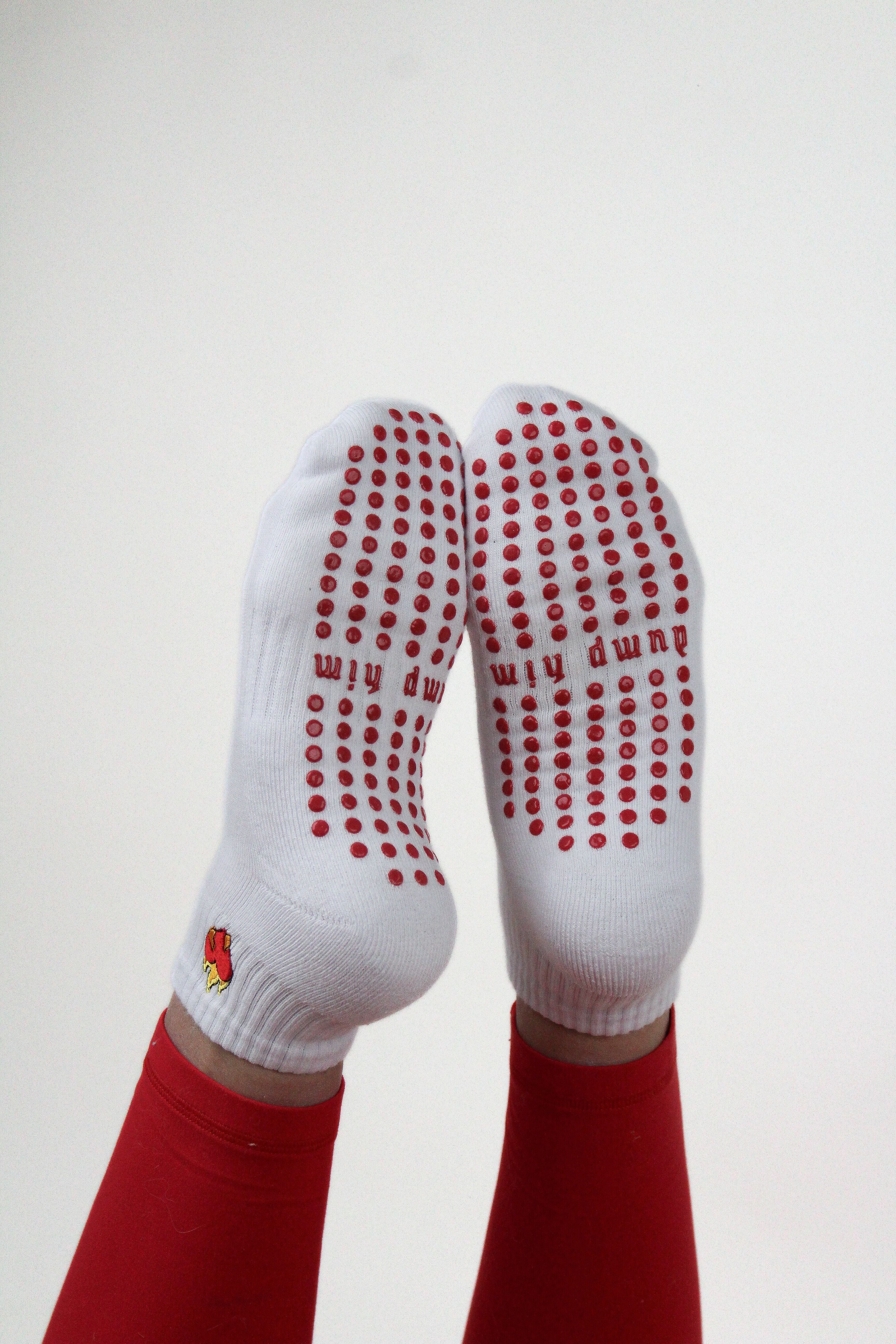 White Dump Him Grip Socks with red anti-slip dots worn by person in red leggings against white background